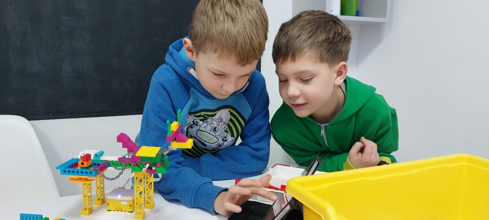 Dwójka dzieci składająca razem zestaw klocków LEGO Education podczas warsztatów robotyki